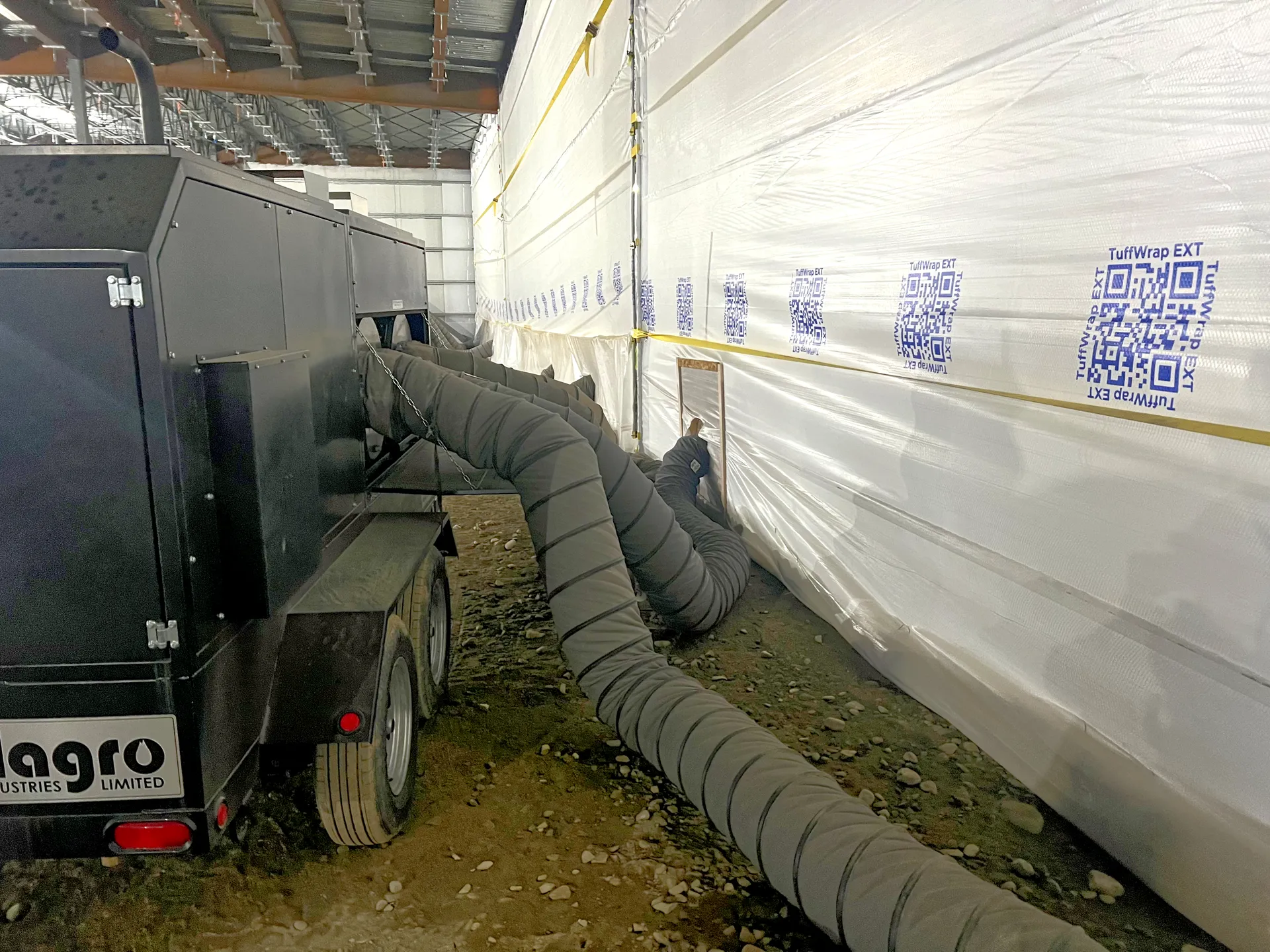 A big industrial heater with hoses coming out of the side attached to the EXT wall in order to heat the space. 